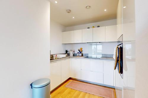 a kitchen with white cabinets and a wooden floor at 2Bed Apartment with Lift and Balcony - 2min to Station in London
