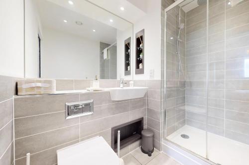 a bathroom with a shower and a sink and a mirror at 2Bed Apartment with Lift and Balcony - 2min to Station in London