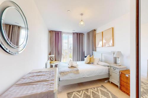 a white bedroom with a bed and a mirror at 2Bed Apartment with Lift and Balcony - 2min to Station in London