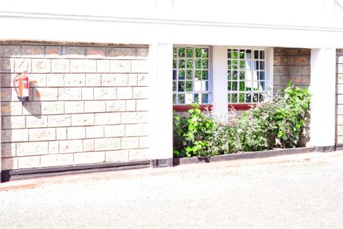 ein weißes Backsteinhaus mit einem Fenster und einem roten Telefon in der Unterkunft Emerald Gardens Airbnb in Kitale