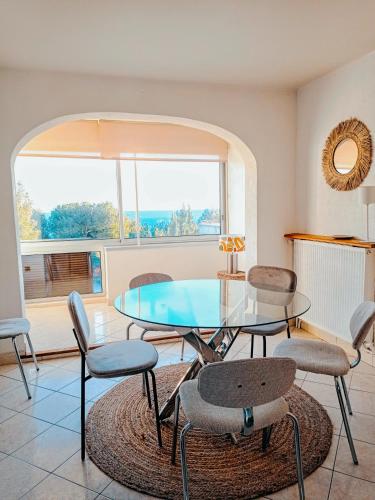 une salle à manger avec une table et des chaises en verre dans l'établissement BLEU CASSIS-VINTAGE -3 Ch- Magnifique vue mer- Parking gratuit et Jardin, à Cassis