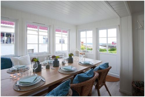 una sala da pranzo con tavolo e alcune finestre di Olsens Pensjonat a Veiholmen