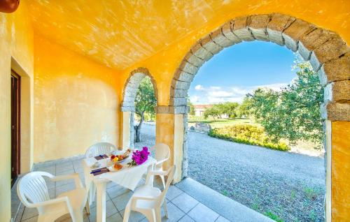 a table and chairs on a porch with an archway at Residence with swmming-pool in Badesi, apartments with private outdoor area in Badesi