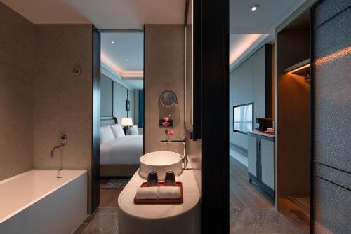 a bathroom with a bath tub and a bedroom at Empark Grand Hotel Beijing in Beijing