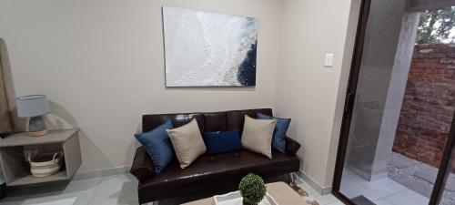 金伯利的住宿－Hub Accomodation，客厅里配有带蓝色枕头的棕色皮沙发