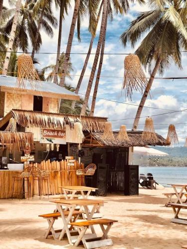 einen Strand mit Tischen, Stühlen und Palmen in der Unterkunft casa lovena by the sea in Lianga