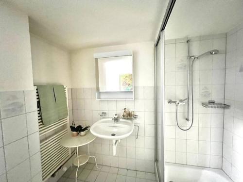 La salle de bains blanche est pourvue d'un lavabo et d'une douche. dans l'établissement Apartment Glärnisch, à Ennenda