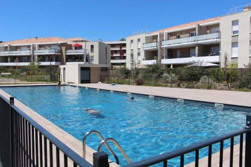 une grande piscine devant un immeuble dans l'établissement Charmant T2 avec piscine, à La Londe-les-Maures