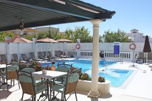 a patio with a table and chairs next to a pool at Hotel Al Sur De Chipiona by YouRoom in Chipiona