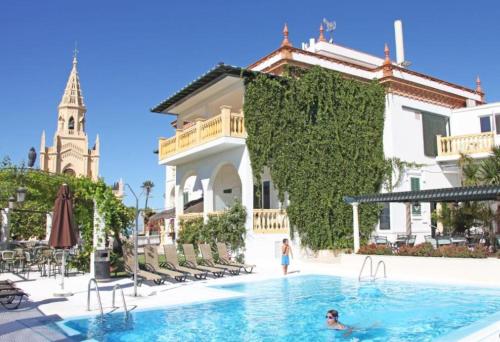 a person in a swimming pool next to a building at Hotel Al Sur De Chipiona by YouRoom in Chipiona