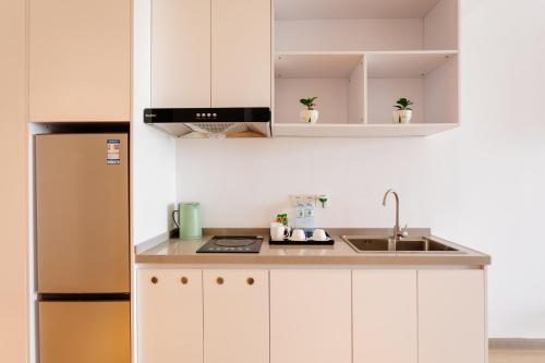 a kitchen with white cabinets and a stainless steel refrigerator at The Q Residence Vientiane in Vientiane