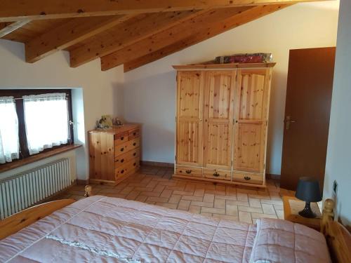 a bedroom with a large bed and a wooden cabinet at Mansarda Dolomitica in Ronzo Chienis