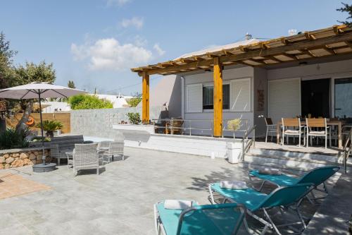 a patio with chairs and tables and a house at Villa Perla in Lardos