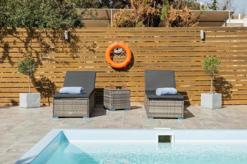 two chairs and a swimming pool in front of a wooden fence at Villa Perla in Lardos