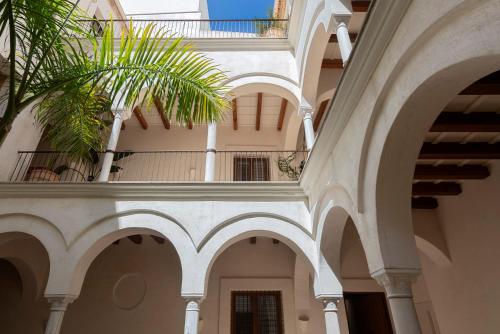 a building with arches and a building with a palm tree at Casa del Rey Sabio in Seville