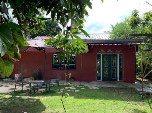 a red house with chairs and a table in the yard at Fusion Villa in Bedung