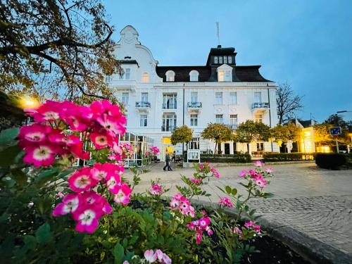 ein großes weißes Gebäude mit rosa Blumen davor in der Unterkunft Göbel`s Hotel Quellenhof in Bad Wildungen