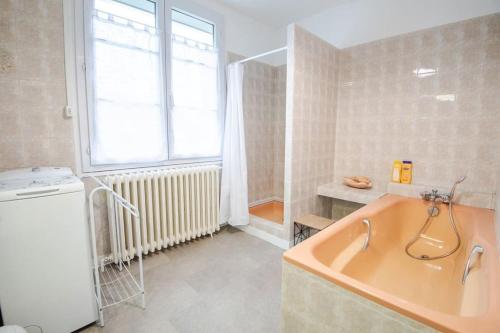 baño con bañera, lavabo y ventana en Parenthèse champêtre : Maison 7 pers., en Truyes