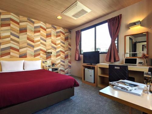 a hotel room with a bed and a desk with a computer at Hotel New Gaea Yakuin in Fukuoka