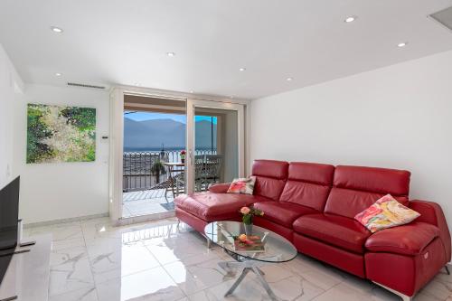 un soggiorno con divano rosso e tavolo in vetro di Red View Apartment - Happy Rentals a Ronco sopra Ascona