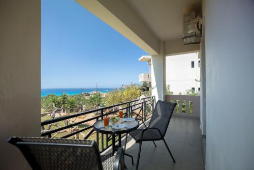 a balcony with a table and chairs and the ocean at Kalami Apartments in Falasarna