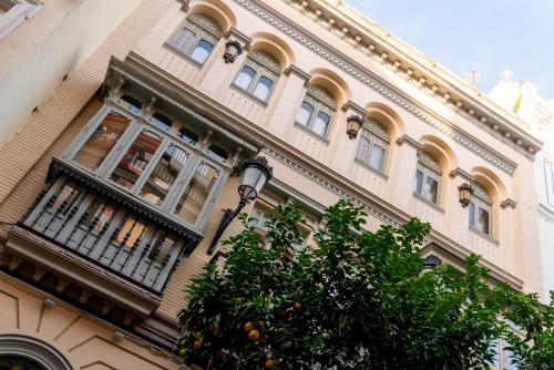 a building with an orange tree in front of it at Arco de la Seda - Hotel Boutique in Seville