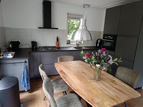 a kitchen with a wooden table with a vase of flowers on it at Bosvilla Lochem - Luxe en privacy in de natuur in Lochem