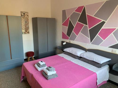 a bedroom with a pink bed with towels on it at Hotel Splendor in Tortolì