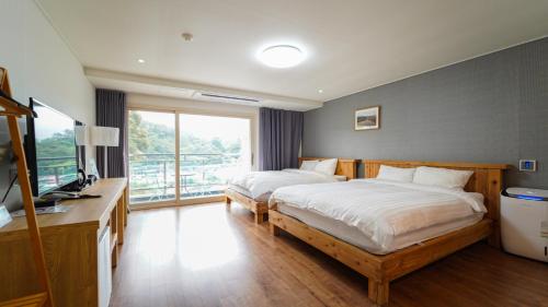 a bedroom with two beds and a desk and a television at 천지연크리스탈 하버39호텔 in Seogwipo