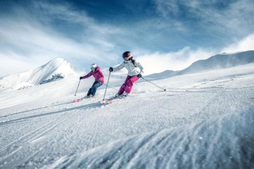 two people are skiing down a snow covered slope at APPARTEMENT Brix in Pichl