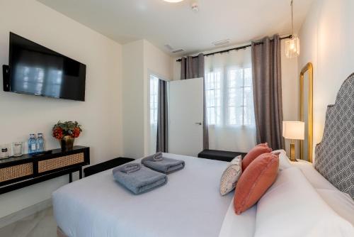 a bedroom with a white bed and a tv at Arco de la Seda - Hotel Boutique in Seville