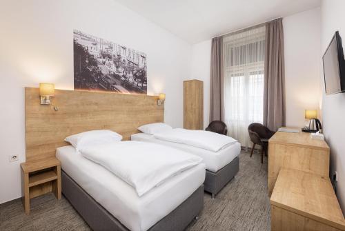 ブダペストにあるシティ ホテル リングのベッド2台とデスクが備わるホテルルームです。