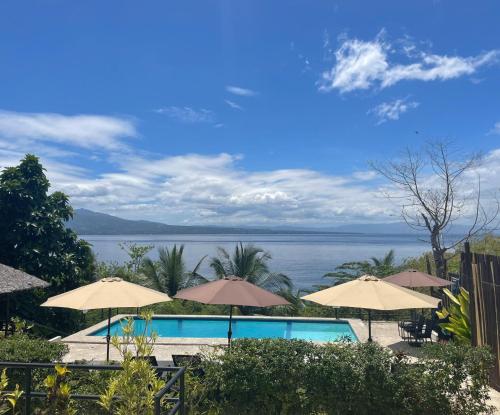 a pool with umbrellas and a view of the water at Masayahin Cabanavillas in Santander