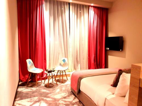 a bedroom with red curtains and a bed and two chairs at FORTUNE ATRIUM HOTEL in Dubai