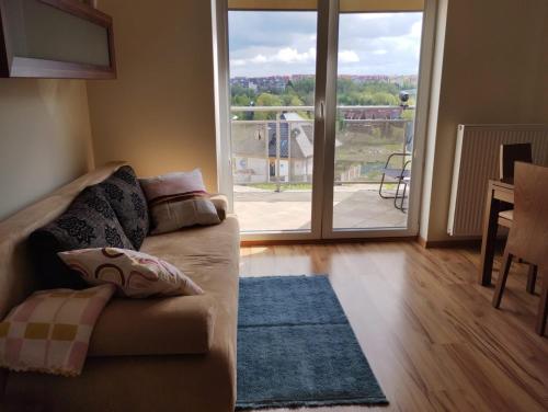 a living room with a couch and a large window at Apartament Gardena II Olsztyn Jaroty in Olsztyn