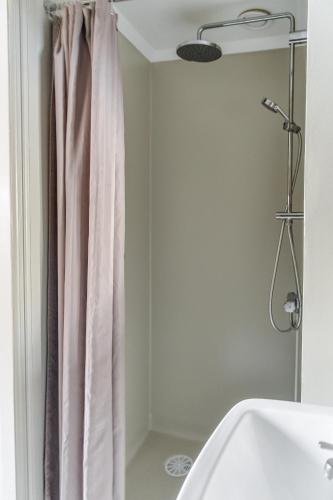 y baño con cortina de ducha y lavamanos. en Brunnsvik Hotell & Konferens en Ludvika