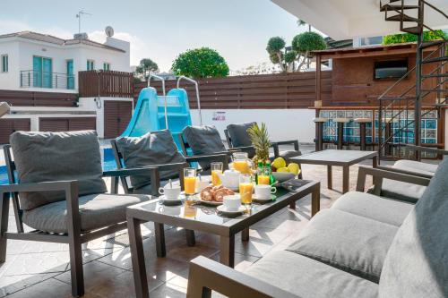 a patio with chairs and tables and a slide at Seafront Protaras Villas in Protaras
