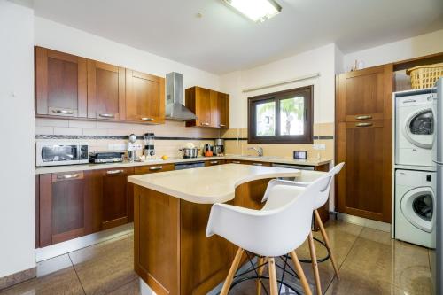a kitchen with wooden cabinets and white appliances at Seafront Protaras Villas in Protaras