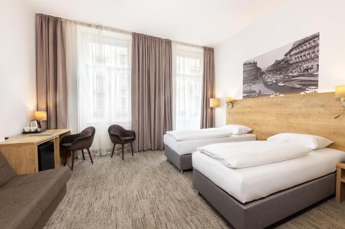 um quarto de hotel com duas camas e um sofá em City Hotel Ring em Budapeste