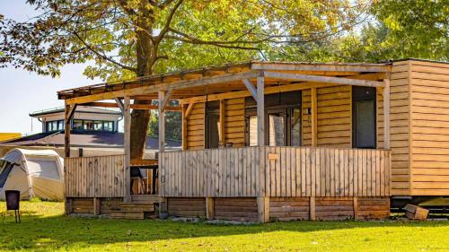 a wooden cabin with a fence and a tent at Mobilna hiška Hupi in Velenje