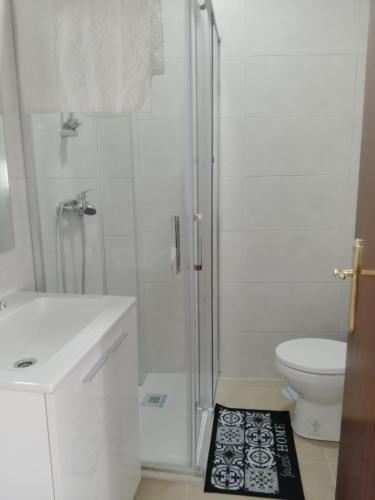 uma casa de banho branca com um chuveiro e um WC. em Home P.C em Getafe