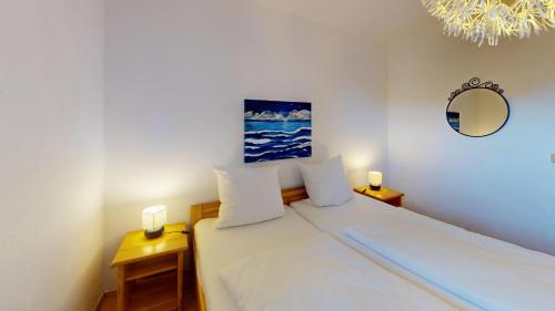 a bedroom with a bed with white sheets and a mirror at Ort Lemkenhafen Kiter in Fehmarn
