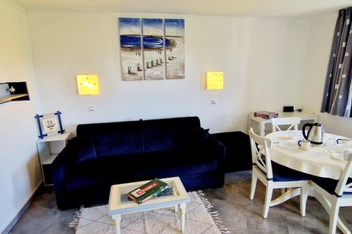 ein Wohnzimmer mit einem blauen Sofa und einem Tisch in der Unterkunft "LE GREEN" Appartement, 4 personnes, accès piscines gratuit in Talmont