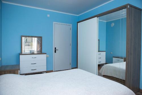 a blue bedroom with a bed and a mirror at Chakvi Lux House in Chakvi