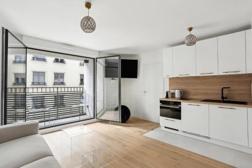 a kitchen with white cabinets and a large window at Chic et minimaliste studio Batignolle/Montmartre by Weekome in Paris