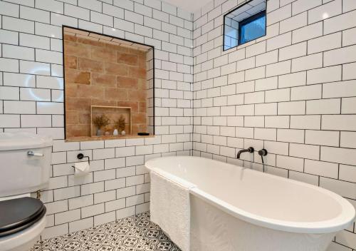 a white bathroom with a tub and a toilet at Sanabrin and Little Brin in Weasenham