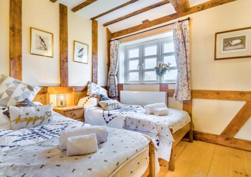 two beds in a room with a window at Orchard Cottage in East Dereham