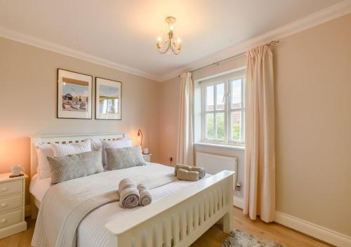a bedroom with a large white bed and a window at 2 Oaklands Cottage in Holt