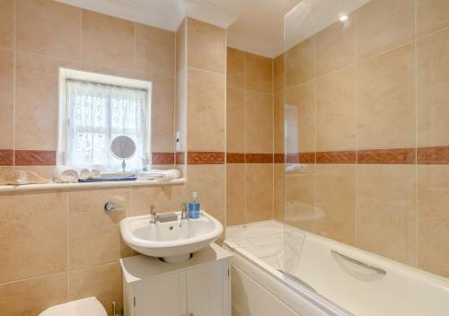 a bathroom with a sink and a toilet and a tub at 2 Oaklands Cottage in Holt