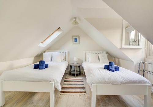 2 bedden in een zolderkamer met blauwe kussens bij Marsh View in Salthouse